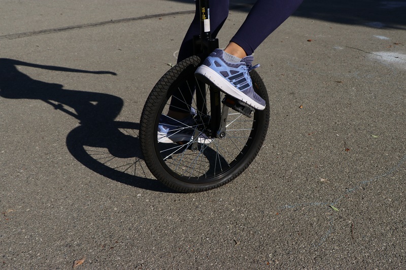 Image très centrée sur la roue d'un monocycle et baskets du sportif