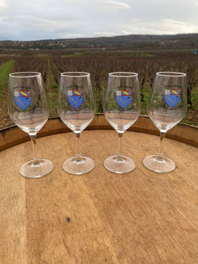 Quatre verres à vin sur un tonneau au milieu des vignes